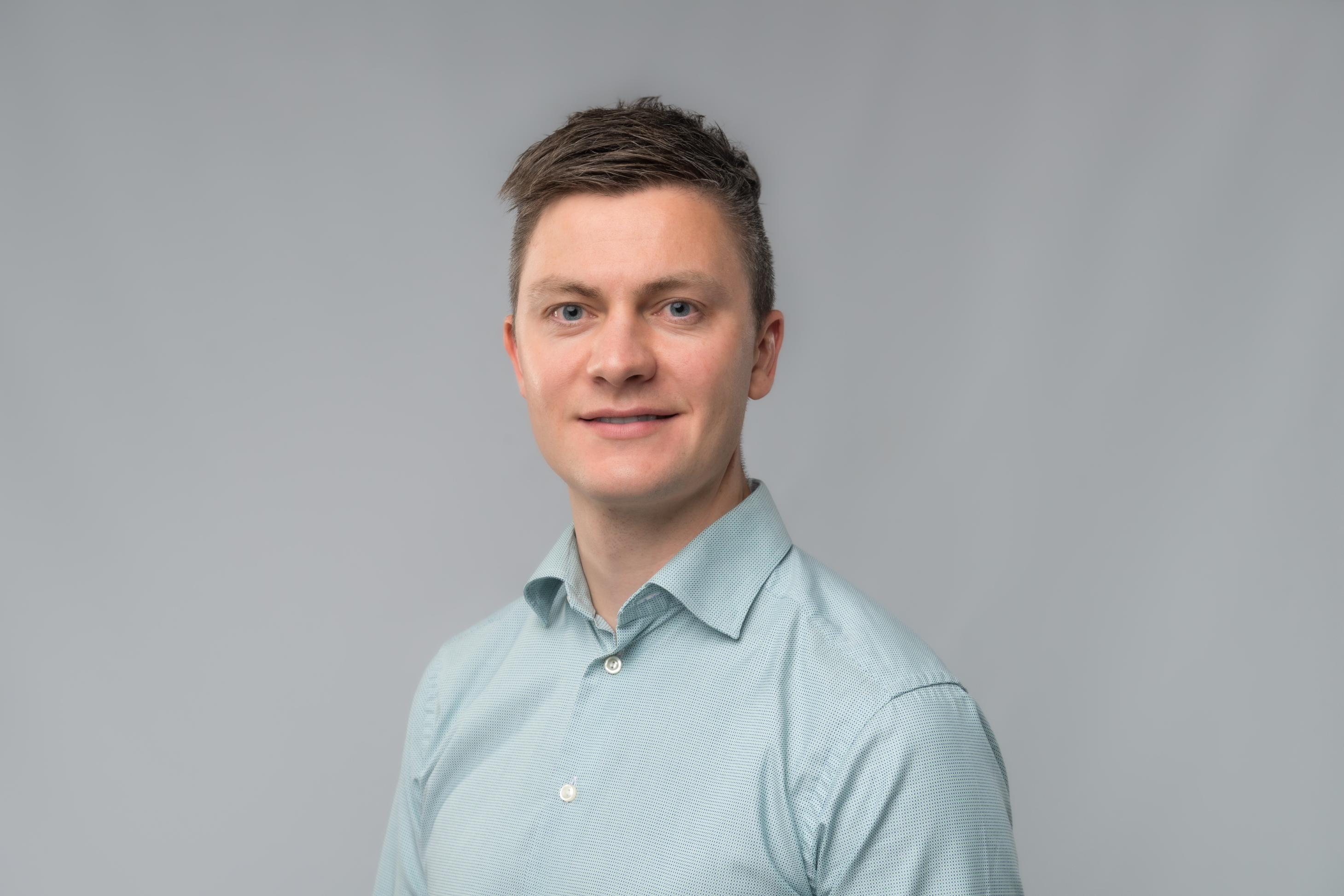 Mann med mørkt kort hår og lys blå skjorte